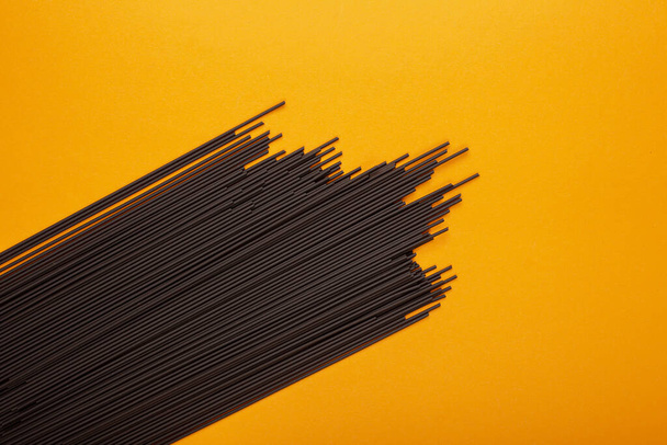 Schwarze Spaghetti auf gelbem Hintergrund - Foto, Bild