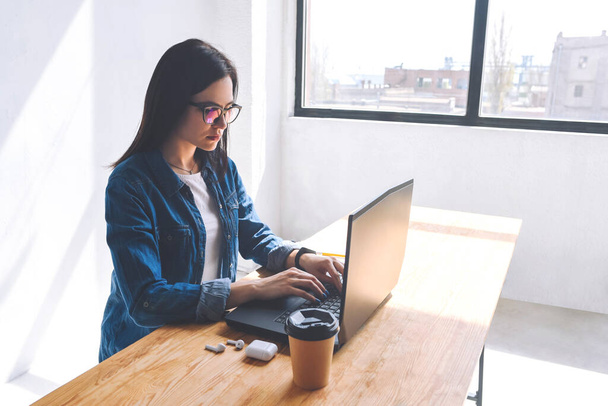 Dívka s brýlemi sedí a pracuje u laptopu. Pracovat doma. Freelancer. - Fotografie, Obrázek