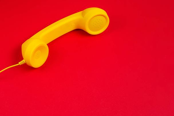 Yellow handset on red background. Copy space. - Фото, изображение