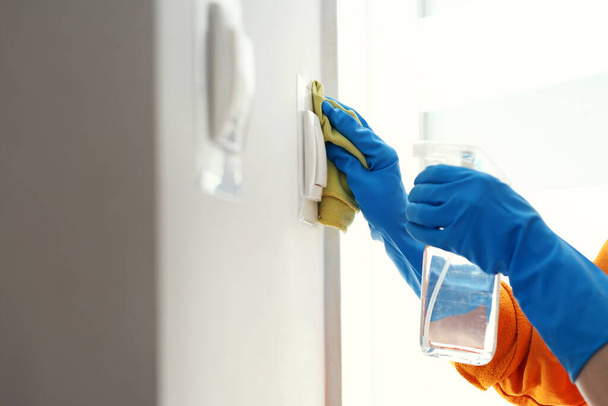 Contact disinfection, disinfection of switches. Prevention and prevention of infection. The woman disinfects the light switches. - Foto, afbeelding