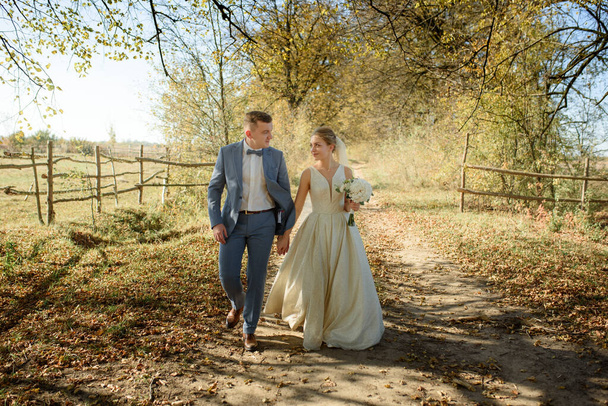 Молода красива пара ходить у своїх весільних сукнях в осінньому парку
. - Фото, зображення