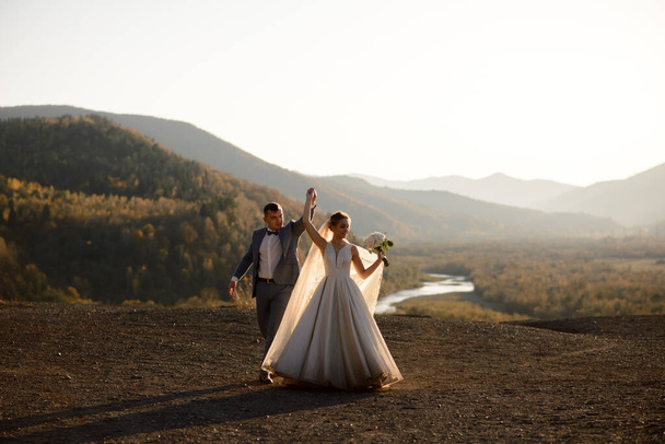 Hochzeitsfotosession des Brautpaares in den Bergen. Fotoshooting bei Sonnenuntergang. - Foto, Bild