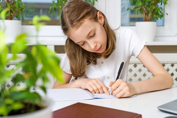 Schulmädchen macht ihre Hausaufgaben zu Hause. Quarantäne-Konzept. - Foto, Bild