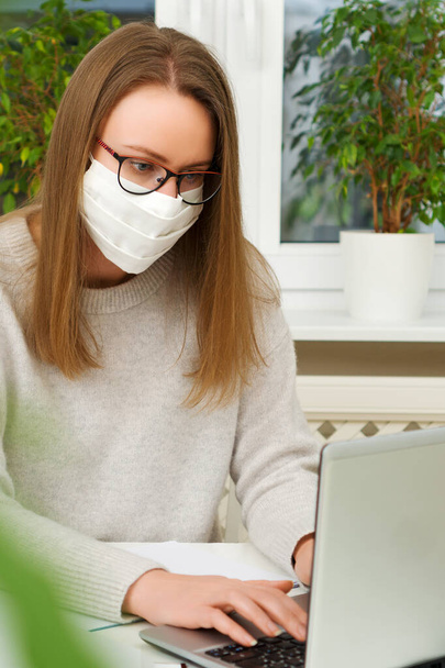 Woman in glasses and mask works from home. Quarantine concept. - Photo, image