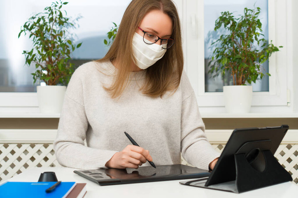 Woman designer in glasses and mask works from home. Quarantine concept. - Photo, Image