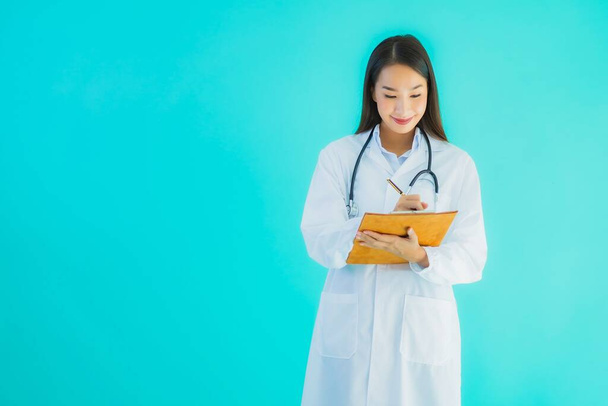 Portrét krásné mladé asijské lékař žena s prázdnou kartou billboard banner na modrém izolovaném pozadí - Fotografie, Obrázek