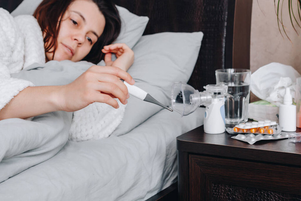 Jonge zieke vrouw in bed drinkt pillen. kopieerruimte - Foto, afbeelding