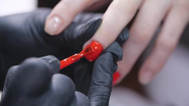 Handen van een vrouw die rode nagellak aanbrengen in een schoonheidssalon - Video