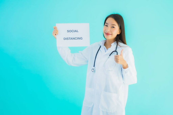 Портрет красивая молодая азиатская врач женщина с плакатом бумаги с социальным дистанцирующим словом для защиты от covid19 или коронавируса
 - Фото, изображение