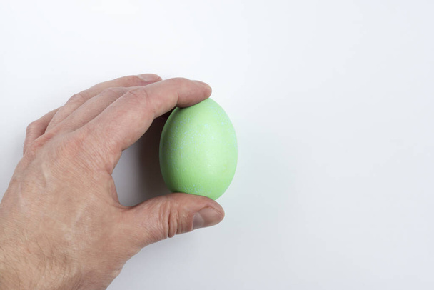 Рука тримає зелене пасхальне яйце на білому тлі, концепція
 - Фото, зображення