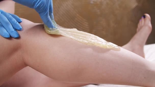 Egy nő a Spa-ban, akinek a lábát gyantáztatják szőrtelenítésért lassított felvételen - Felvétel, videó