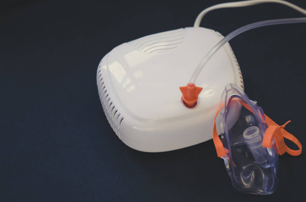 White nebulizer with a mask on a black background. Lung ventilation. Help with the virus. Medicine. - Foto, Imagem