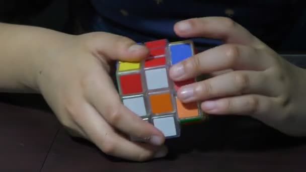 Egy lány próbálja megoldani rubik kocka forgatásával blokkok - Felvétel, videó