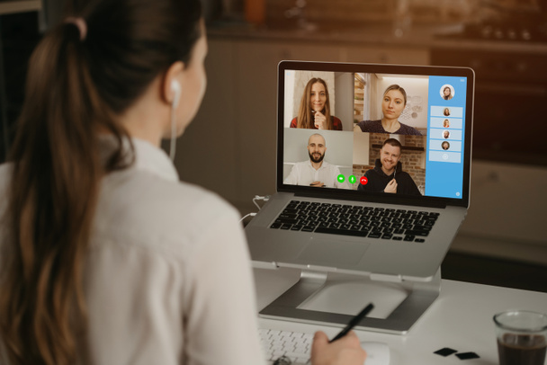 A rearview of a businesswoman at home in a video conference with her colleagues during an online meeting. Partners in a video call. Multiethnic business team having a discussion in an online meeting. - Photo, Image