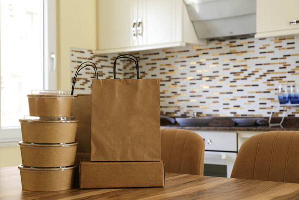 Bunch of blank disposable containers for takeout food stacked with paper bags and boxes with copy space for brand's logo. Close up shot of eco friendly to go carton bowls on table. - Photo, Image