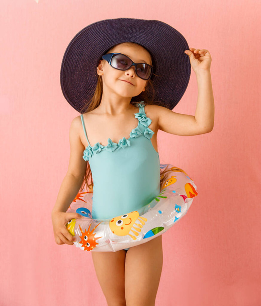 little cheerful girl in a swimsuit, hat and glasses on a background - Photo, Image