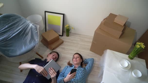 Young couple laying at the floor and relaxing in apartment. Moving to new home - Séquence, vidéo