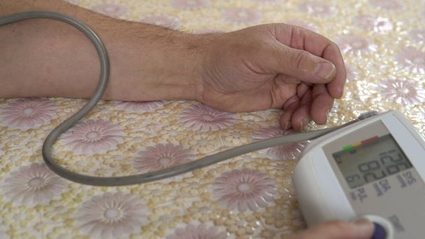 Una persona usa un dispositivo para medir la presión cardiovascular. El hombre se puso el monitor de presión arterial en la mano y midió la presión de cerca.
. - Foto, imagen