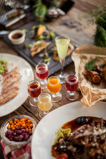 Shots cherry lemon apple cranberry on wooden table at feast with plates daylight restaurant  - Fotoğraf, Görsel