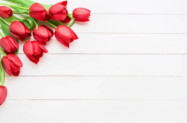 Bouquet of red tulips on white wooden background. Mothers day, Valentines Day, Birthday celebration concept. Copy space for text, top view - Photo, Image