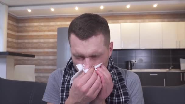 A beteg fiatalember torokgyulladásban és betegségben szenved. Tüsszentés fehér szalvétába és orrspray használata. Fejfájás és rossz érzés. Beteg fickó a konyhában.. - Felvétel, videó