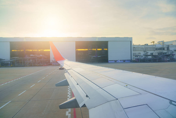 Blick aus dem Innenfenster des Flugzeugs Das Flugzeug parkt auf der Landebahn des Terminals, während es wartet Abteil und Hangar-Hintergrund Sonnenlicht und Fackeln in BANGKOK THAILAND - Foto, Bild