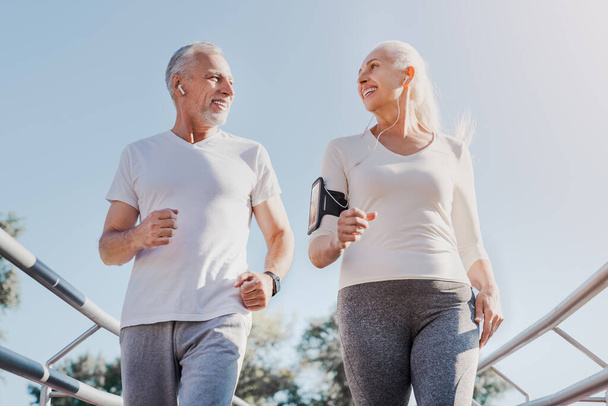 Close up of healthy smiling mature couple jogging in the city at - Foto, Imagem