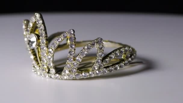 Выставлена бриллиантовая корона из белого металла, используемая в качестве броши для волос
 - Кадры, видео