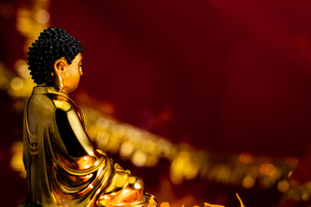 plano lateral de la estatua de buddha sentado delante de fondo gloden rojo borroso con espacio de copia. fe y concepto beleif
 - Foto, imagen