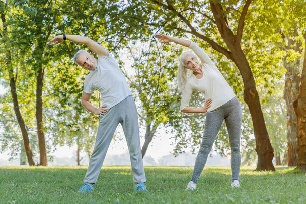 Full length of senior couple stretching together in park outdoor - Fotoğraf, Görsel