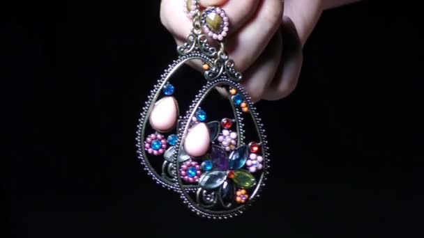 Uma mulher mostra dois brincos de jóias cravejado de gema nos dedos, par
 - Filmagem, Vídeo