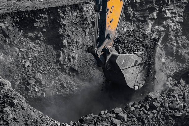 Excavatrice jaune travaille et extrait le charbon des entrailles de la terre. Industrie minière à ciel ouvert - Photo, image