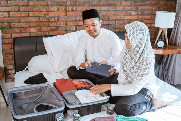 muslim couple preparing clothes on suitcase - Фото, зображення