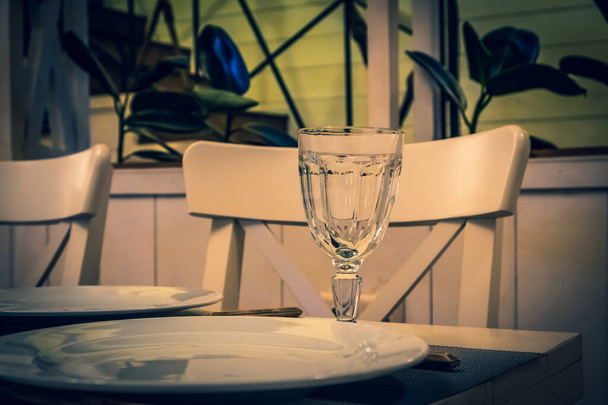  The served table in the restaurant. Clean dishes and appliances on the tablecloth in a cafe. Shiny transparent glasses. White plates. Prepared for the reception of guests. High service. - Photo, Image