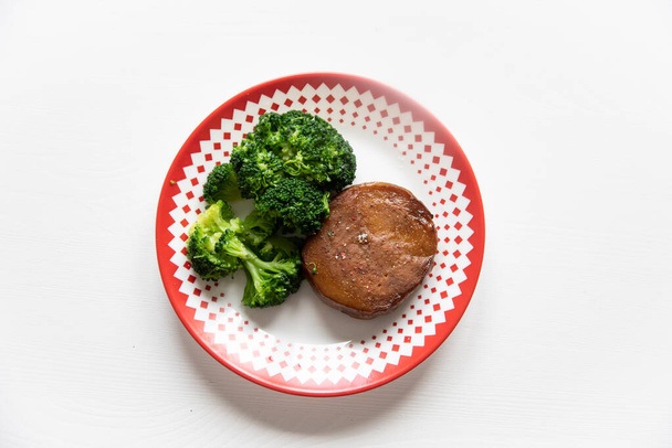 Seitan with broccoli also a knife and a fork in white table - Photo, Image