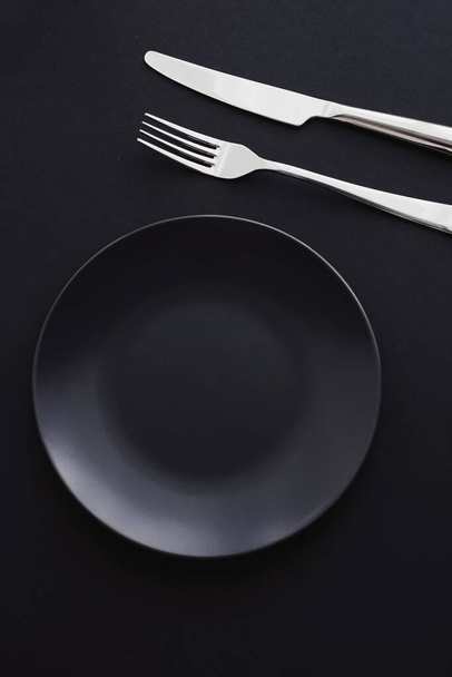 Siyah arka planda boş tabaklar ve gümüş takımlar, bayram yemeği için özel sofra takımı, minimal tasarım ve diyet - Fotoğraf, Görsel