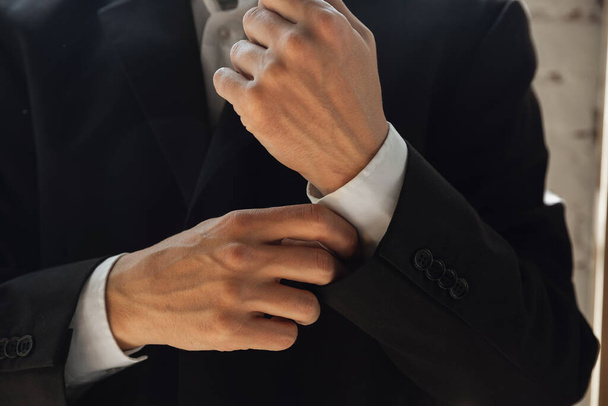 close-up van Kaukasische mannelijke handen, het dragen van klassieke zwarte jas - Foto, afbeelding