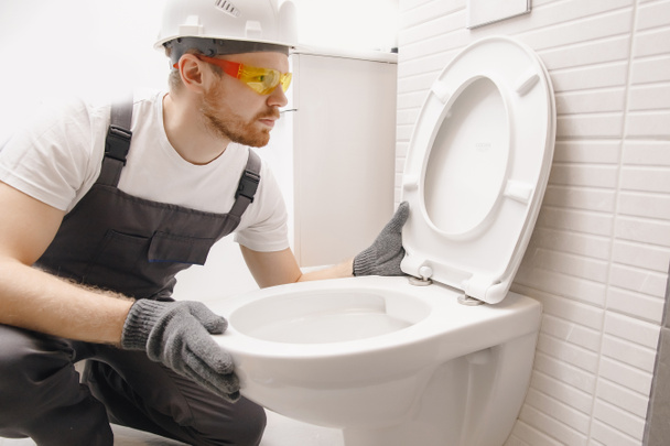 Klempner installiert Toilettenschüssel in Toilette, Arbeit im Badezimmer - Foto, Bild