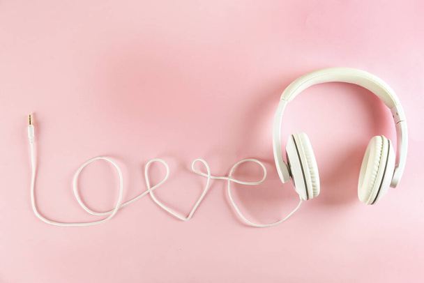 Minimalistic top view composition with white headphones on bright paper textured background with a lot of copy space for your text. Close up, flat lay. - Fotografie, Obrázek