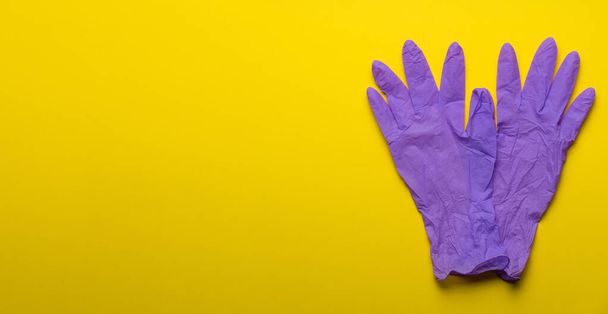 Pair of latex medical gloves on purple background. Protection concept. COVID-19. Epidemic background.  Quarantine background. Medical gloves for protection. Dangerous virus. gloves for test.copy space - Fotó, kép