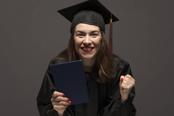 Graduate female student with stubble in eyeglasses wearing black mantle - Foto, imagen
