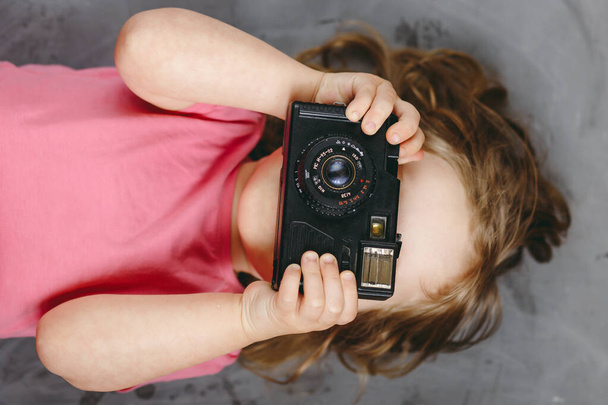 Mała dziewczynka fotograf z aparatem uśmiecha się i zrobić zdjęcie. Widok z góry. - Zdjęcie, obraz