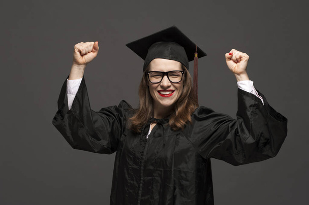 Portrait of graduate adult female student in black graduation gown - Foto, imagen