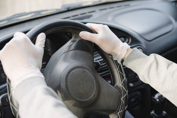 Male driver in a mask and gloves holding the steering wheel, close-up.Prevention of coronavirus infection.Protective measures against coronavirus, covid-19 - Photo, Image