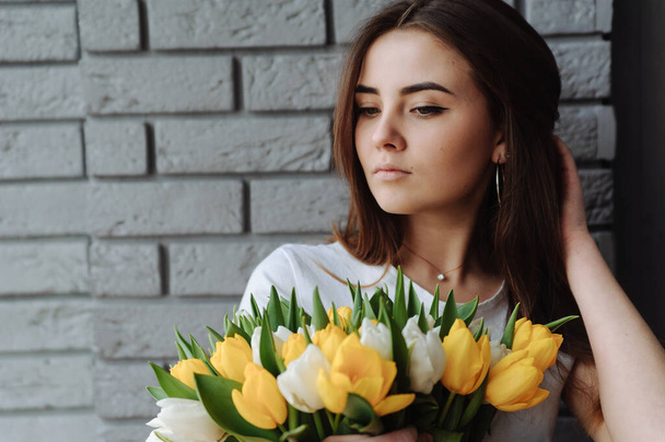 Дівчина з темним волоссям тримає букет тюльпанів в руці
 - Фото, зображення