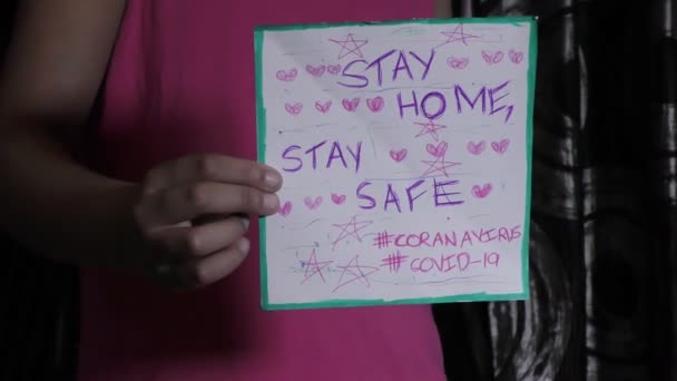 家にいます安全な滞在中にコロナウイルスcovid-19メッセージがカード上の女の子によって示されています. - 映像、動画