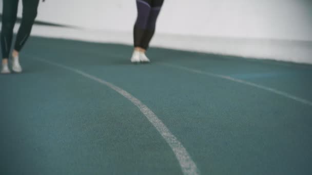 Kaksi nuorta naisurheilijaa Track Shoes Spike Key Spike Key seisoo matalassa aloitusasennossa ja juoksee
 - Materiaali, video