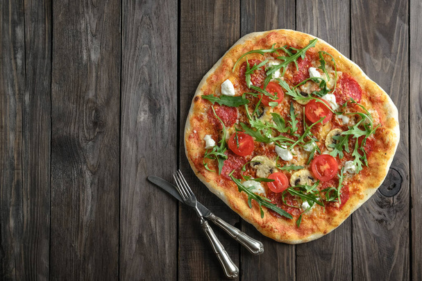 Domowej roboty pizza z mozzarellą, parmezanem, chorizo, grzybami i rukolą na rustykalnym tle top view copy space - Zdjęcie, obraz