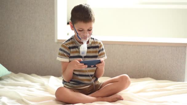 Stay at home quarantine coronavirus pandemic prevention. The child is treated with a nebulizer from COVID-19. Child plays on mobile phone. Prevention epidemic. COVID-19. Inhaler treatment. - Footage, Video