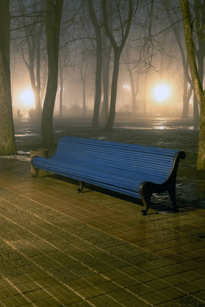 Banc dans le parc de la ville brumeux la nuit à la lumière des lampadaires. Hiver naturel automne fond
 - Photo, image